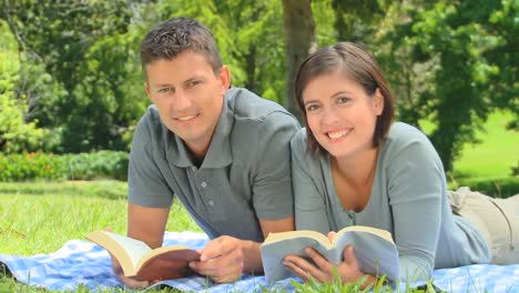 Smiling-young-couple-reading-outdoors