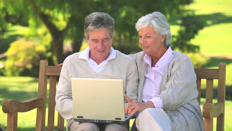 Mature-couple-surfing-on-their-laptop-oudoors