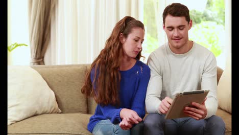 Happy-couple-sitting-on-the-couch-using-the-laptop