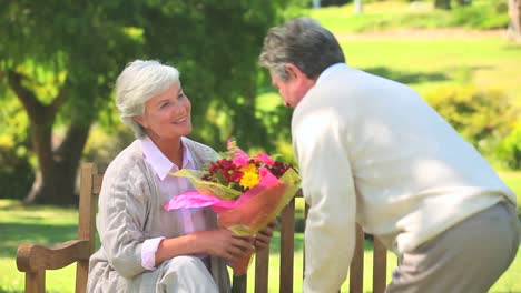 Mature-man-offering-a-bunch-of-flowers-to-his-wife