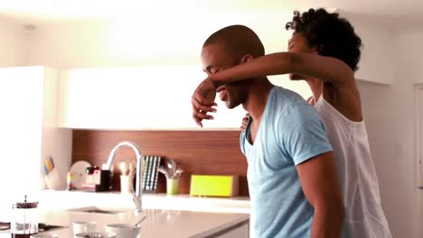Smiling-couple-doing-piggyback-in-the-kitchen-