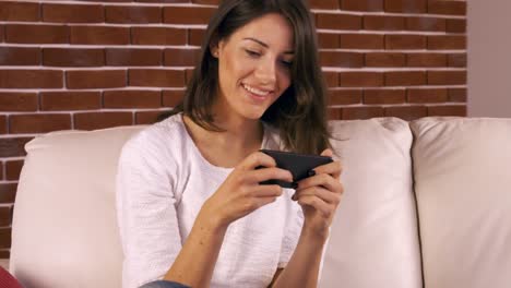 Smiling-woman-texting-on-the-sofa-