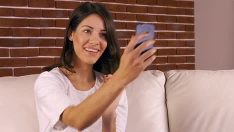 Smiling-woman-taking-selfie-on-the-sofa-
