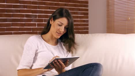Smiling-woman-using-tablet-on-sofa