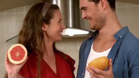 Smiling-young-couple-holding-half-of-grapefruit