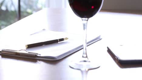 Red-wine,-documents-and-smartphone-on-table