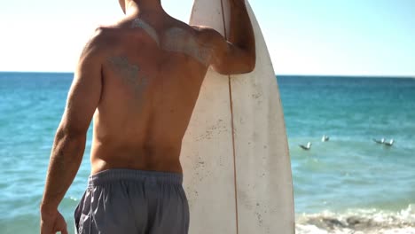 Man-holding-surfboard-on-beach