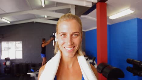 Beautiful-woman-with-towel-around-her-neck-standing-in-gym