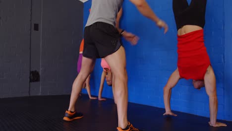 Fitnesstrainer,-Der-Menschen-Beim-Handstand-Unterstützt