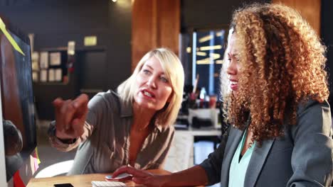 Businesswoman-interacting-with-coworkers-while-working-on-computer