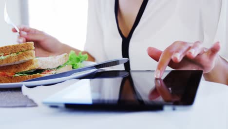 Woman-eating-lunch-and-using-tablet-computer