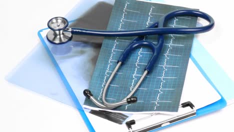 Medical-folders-and-stethoscope-turning-against-white