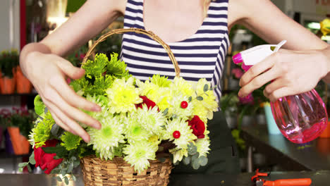 Female-florist-spraying-water-on-flowers-in-flower-shop