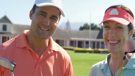 Portrait-of-smiling-couple-standing-with-golf-club
