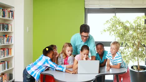 Teacher-and-kids-using-laptop-in-classroom