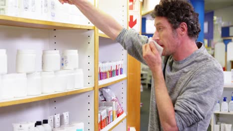 Customer-checking-medicine-box-while-sneezing