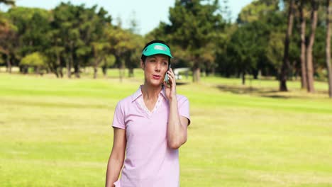 Female-golf-player-talking-on-mobile-phone-while-playing-golf