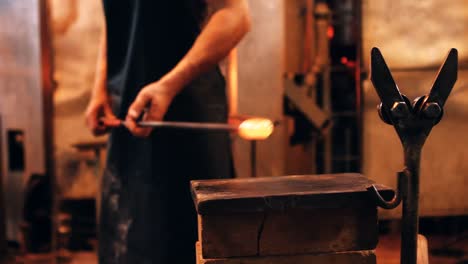 Mid-section-of-glassblower-shaping-a-molten-glass