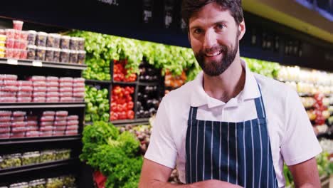Smiling-male-staff-holding-fruit-in-organic-section-of-supermarket
