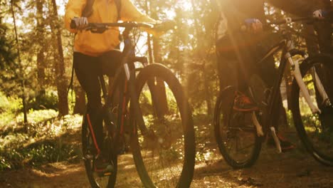 Mountain-biking-couple-riding-in-the-forest-on-a-sunny-day