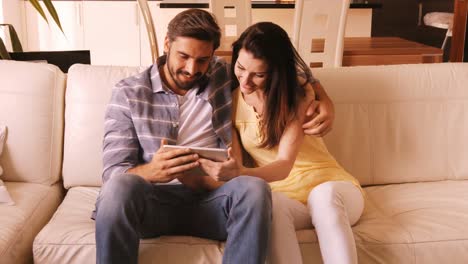 Couple-relaxing-on-sofa-and-using-digital-tablet