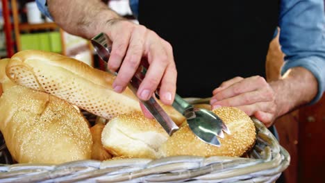 Male-staff-arranging-a-loaf-of-bread-in-wicker-basket