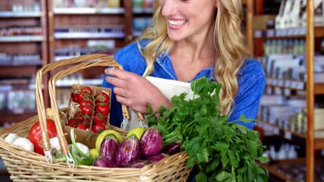 Smiling-female-staff-holding-basket-of-vegetables-in-organic-section