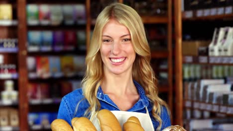 Smiling-woman-holding-a-basket-of-baguettes-in-organic-shop