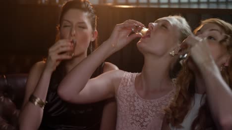 Three-female-friends-toasting-shot-glasses-of-tequila