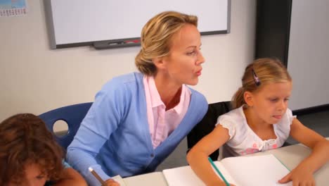 Teacher-helping-kids-with-their-homework-in-classroom