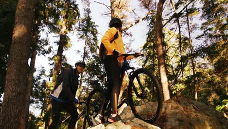 Excited-mountain-biking-couple-standing-on-a-rock