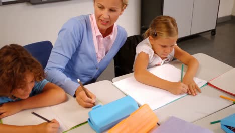 Teacher-helping-kids-with-their-homework-in-classroom