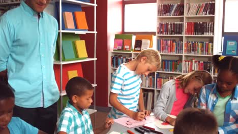 Profesor-Ayudando-A-Los-Niños-Con-Sus-Tareas-En-La-Biblioteca.