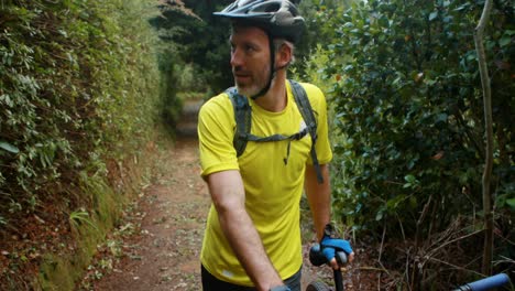 Ciclista-Masculino-Caminando-Con-Bicicleta-De-Montaña-En-El-Bosque