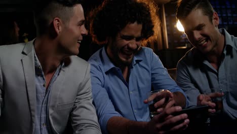 Group-of-happy-friends-looking-at-mobile-phone