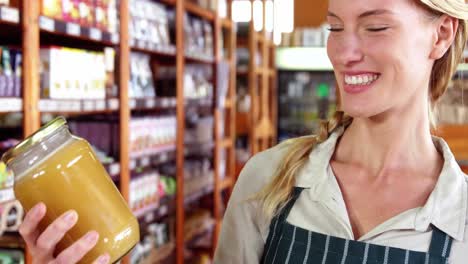 Female-staff-looking-a-jar-of-honey-in-supermarket