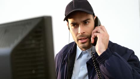 Guardia-De-Seguridad-Hablando-Por-Teléfono-Mientras-Trabaja-En-La-Computadora