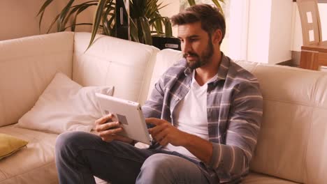 Hombre-Relajándose-En-El-Sofá-Y-Usando-Una-Tableta-Digital