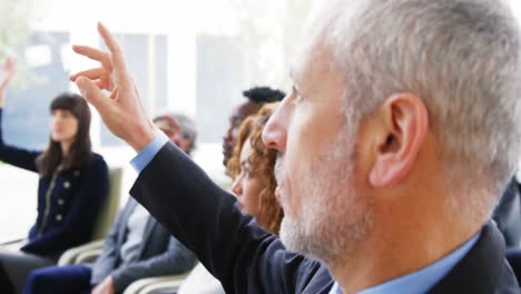 Businesspeople-raising-their-hands-during-a-meeting-