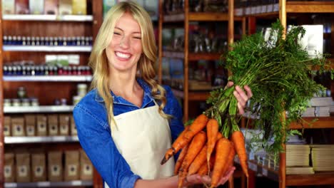 Smiling-staff-holding-bunch-of-carrots-in-organic-section