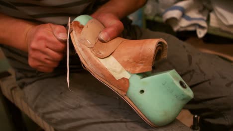 Cobbler-cutting-a-piece-of-leather-on-shoe-last