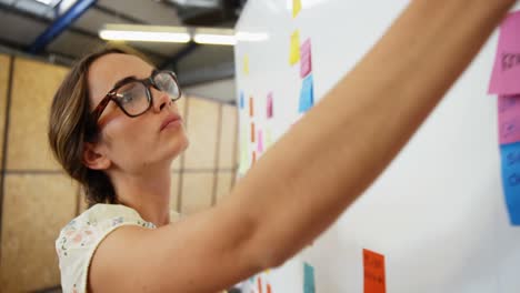 Woman-putting-sticky-notes-on-whiteboard