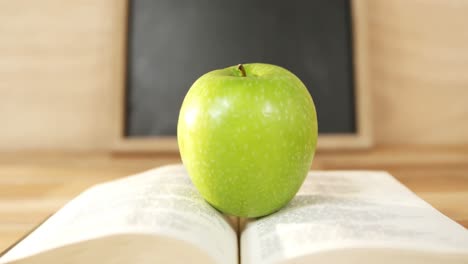 Close-up-of-green-apple-with-open-book