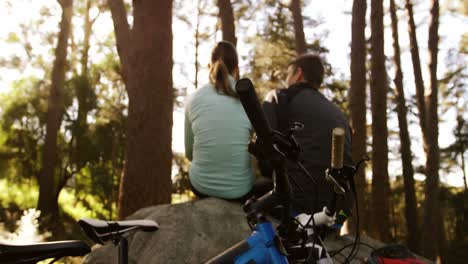 Mountain-biking-couple-taking-a-break-in-the-forest