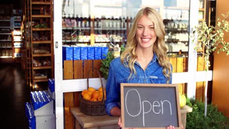 Smiling-owner-holding-open-signboard-in-supermarket