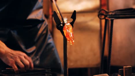 Close-up-of-glassblower-shaping-a-molten-glass