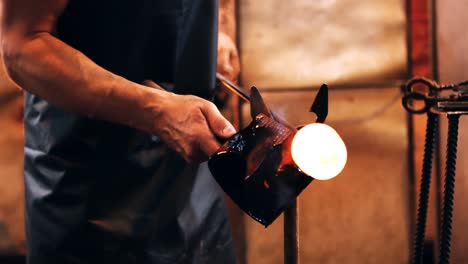 Mid-section-of-glassblower-forming-and-shaping-a-molten-glass