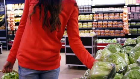 Woman-selecting-vegetable-from-organic-section