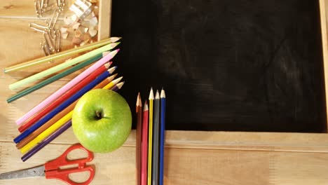 Close-up-of-chalkboard-with-colored-pencil-and-apple