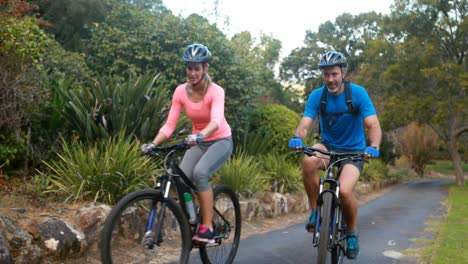 Couple-interacting-while-riding-bicycle-on-road